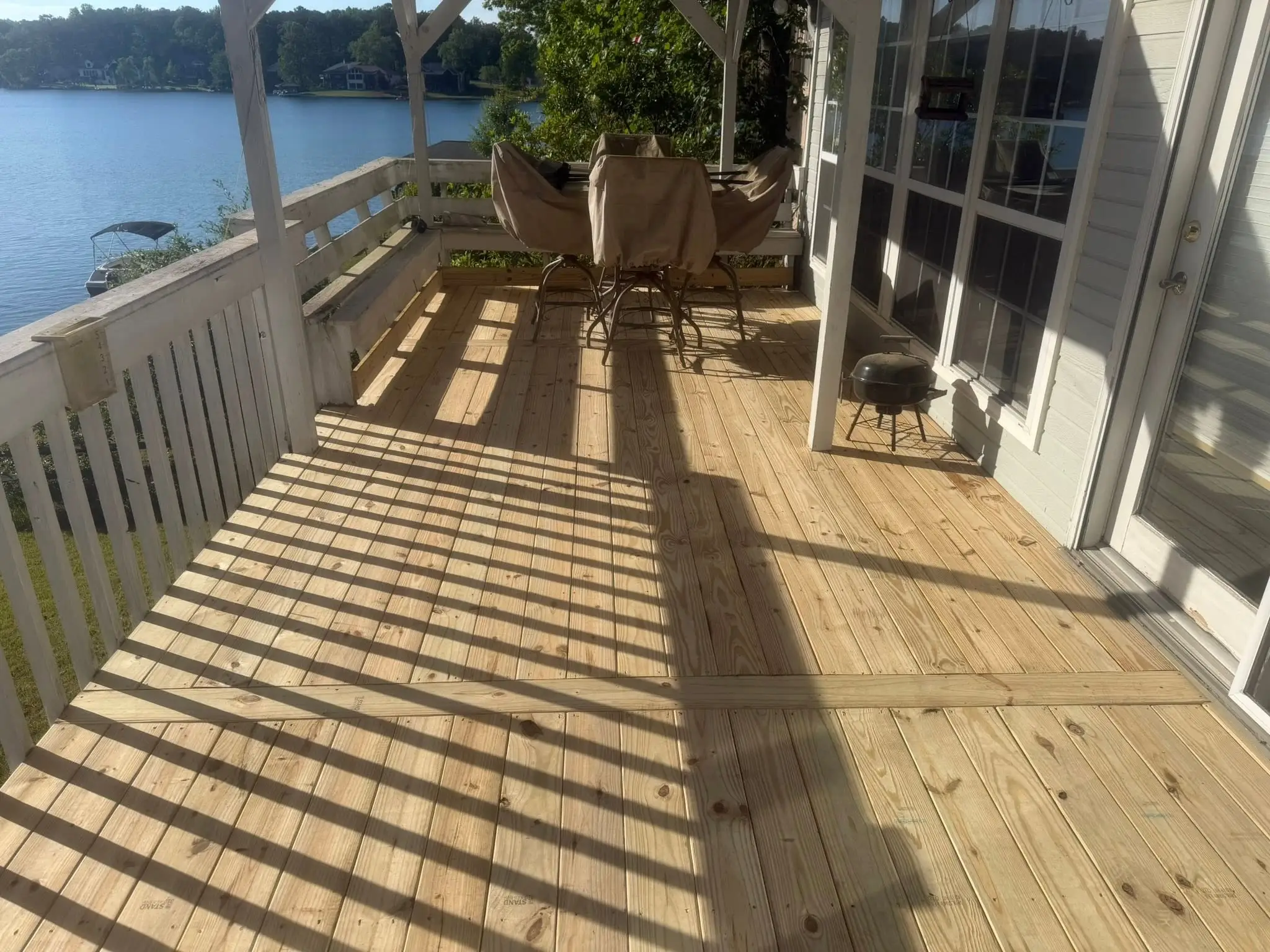 New full-length deck boards beside a white porch rail