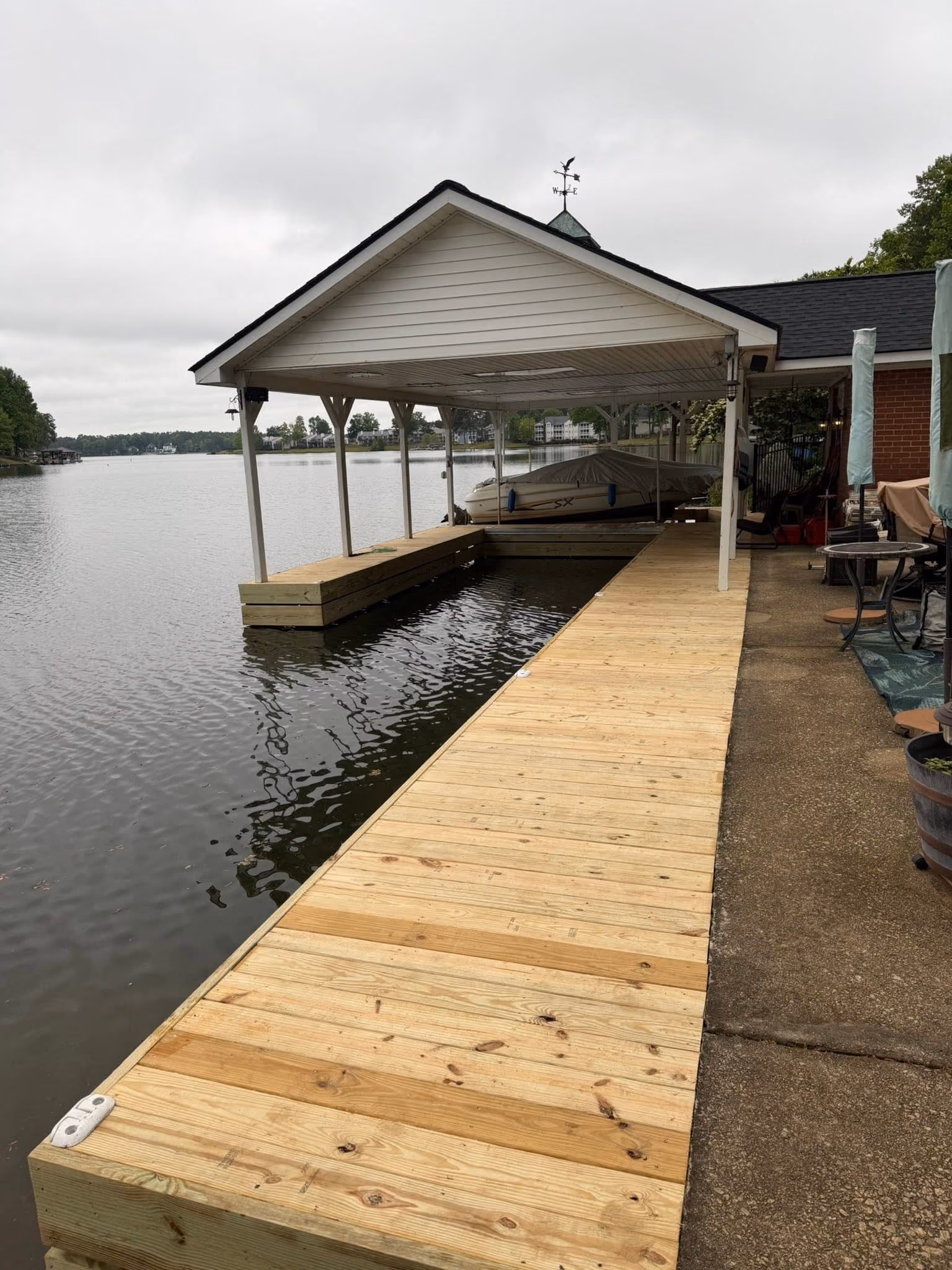 Covered boat dock with a long walkway of new pressure-treated decking and a fresh facial board
