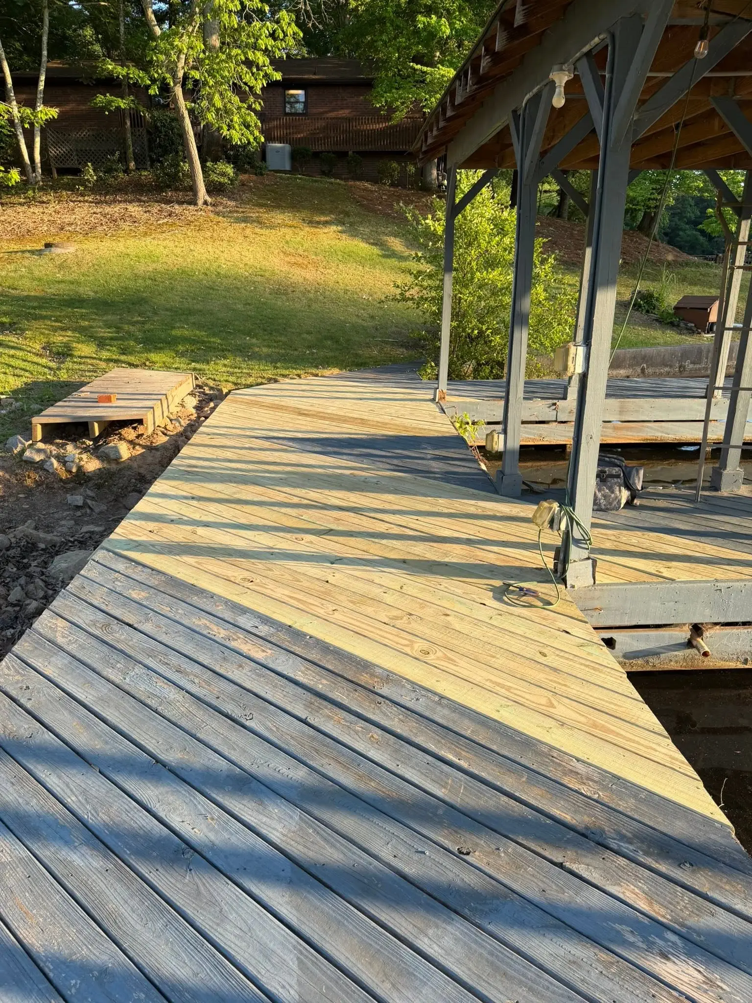 New boards replacing rot on a lake dock walkway at golden hour