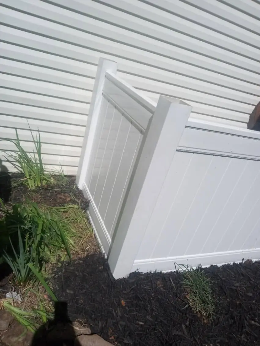 White vinyl privacy fence corner against vinyl siding