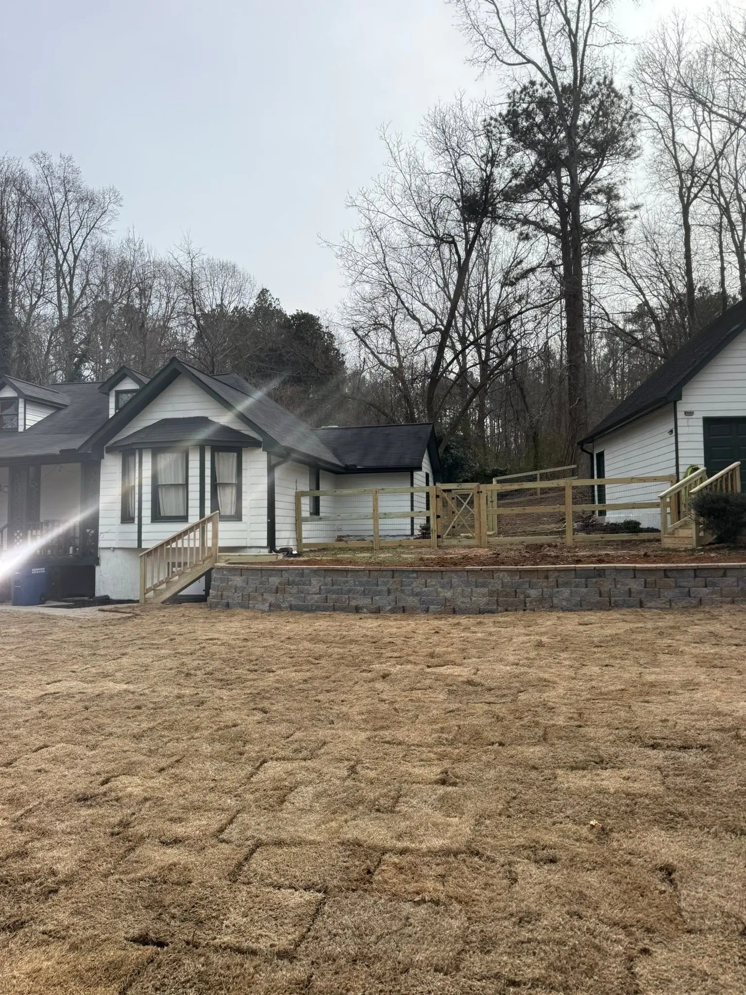 Wood post-and-rail fence running between a farmhouse and its garage, wide angle