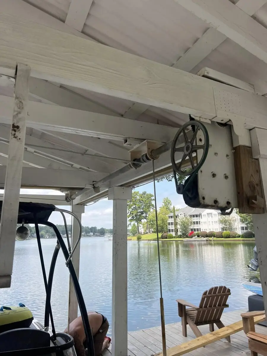 Boat lift winch and cable pulley under the roof of a covered boathouse