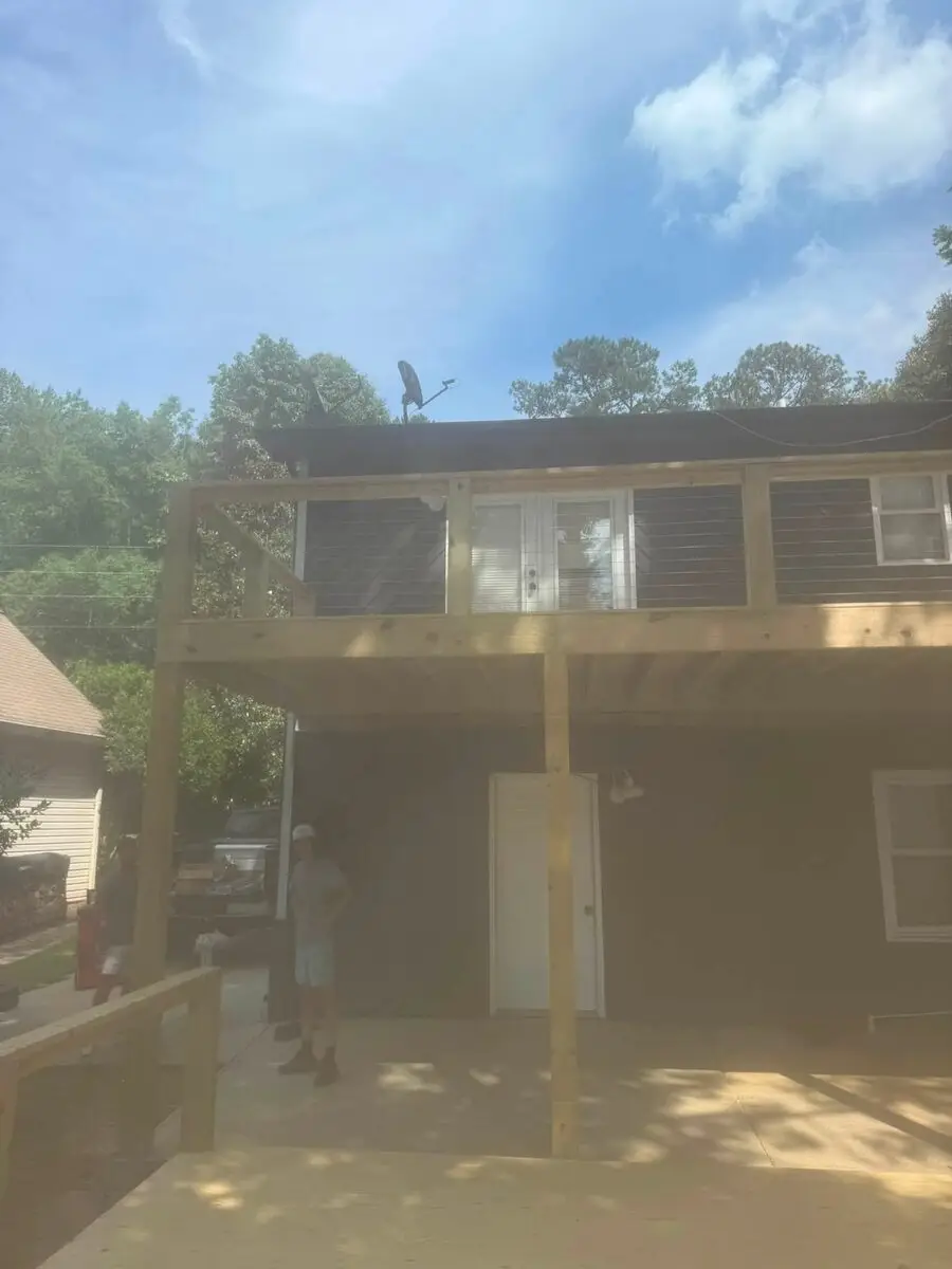 Elevated cable-rail deck on a dark-sided house with crew working below