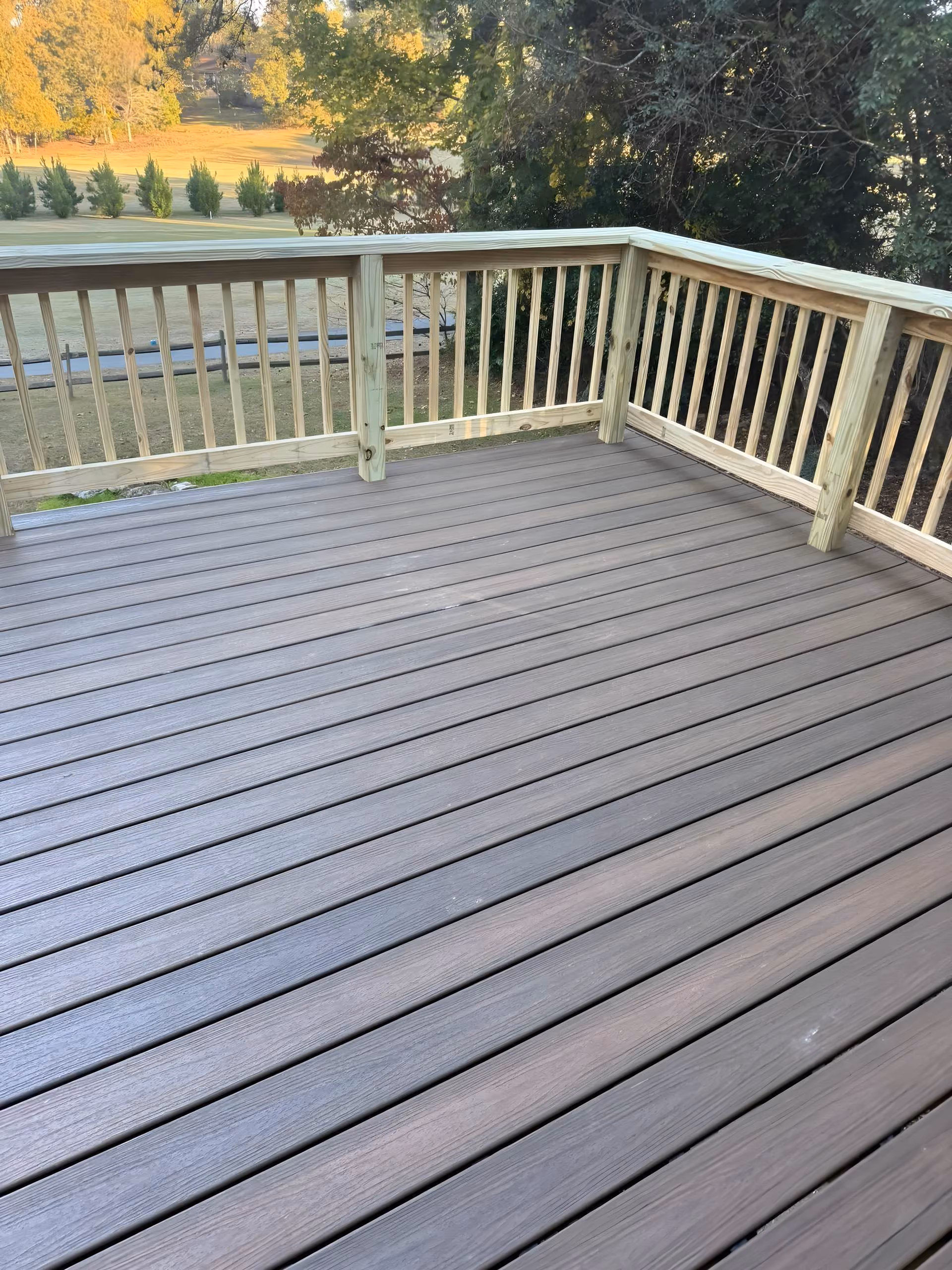 Composite deck flooring with pressure-treated railings overlooking a golf course