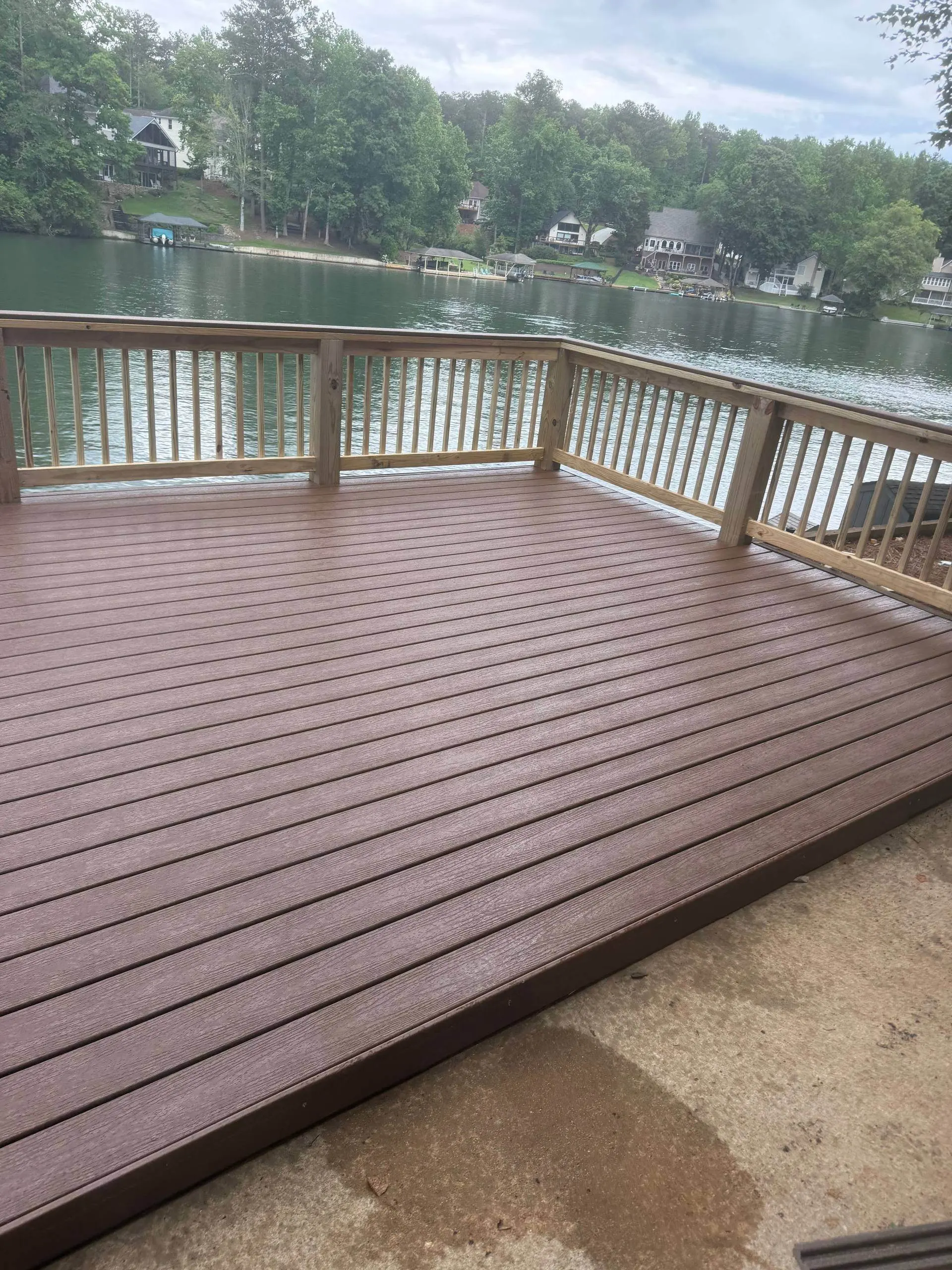 Finished composite deck with a natural wood rail and a lake view