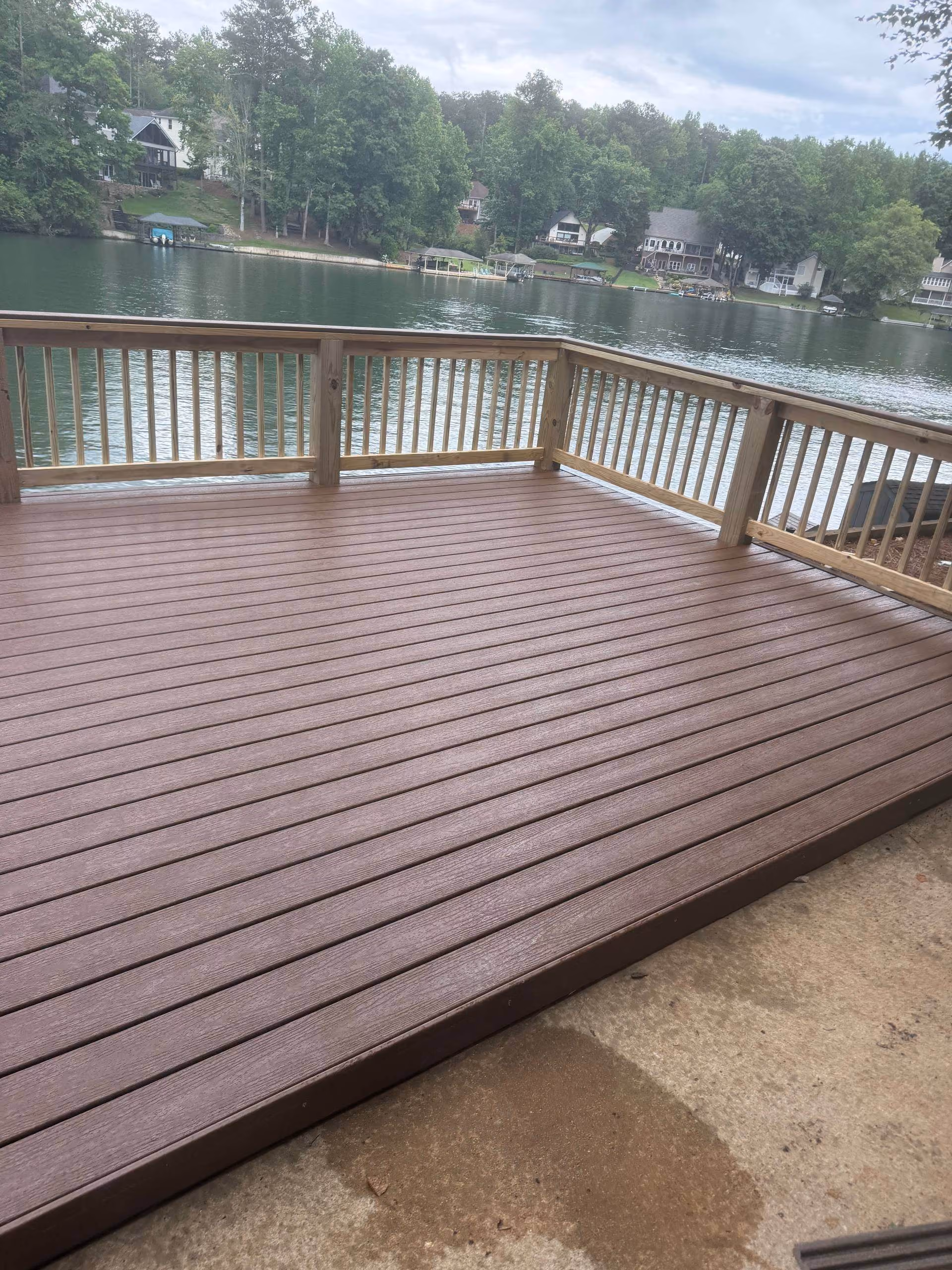 Finished composite deck with a natural wood rail and a lake view