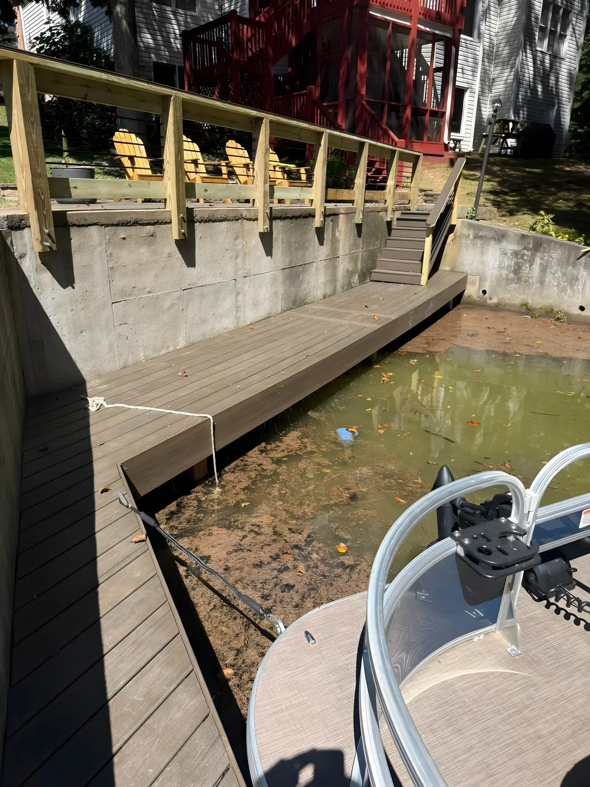 Composite dock decking beside a poured concrete seawall with a pontoon boat in the slip