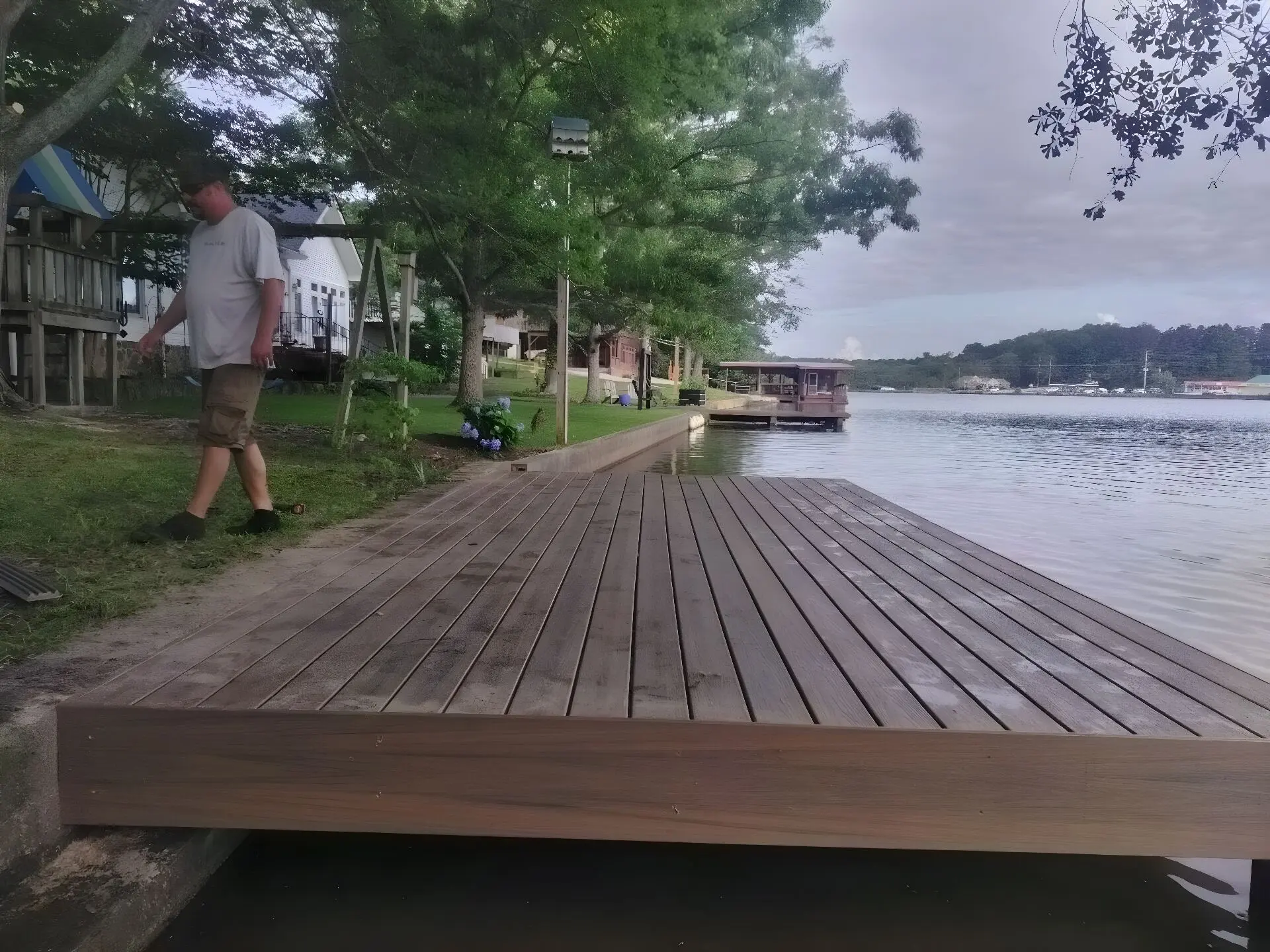 Wide composite dock platform built at the water's edge, a covered dock further down the same shore