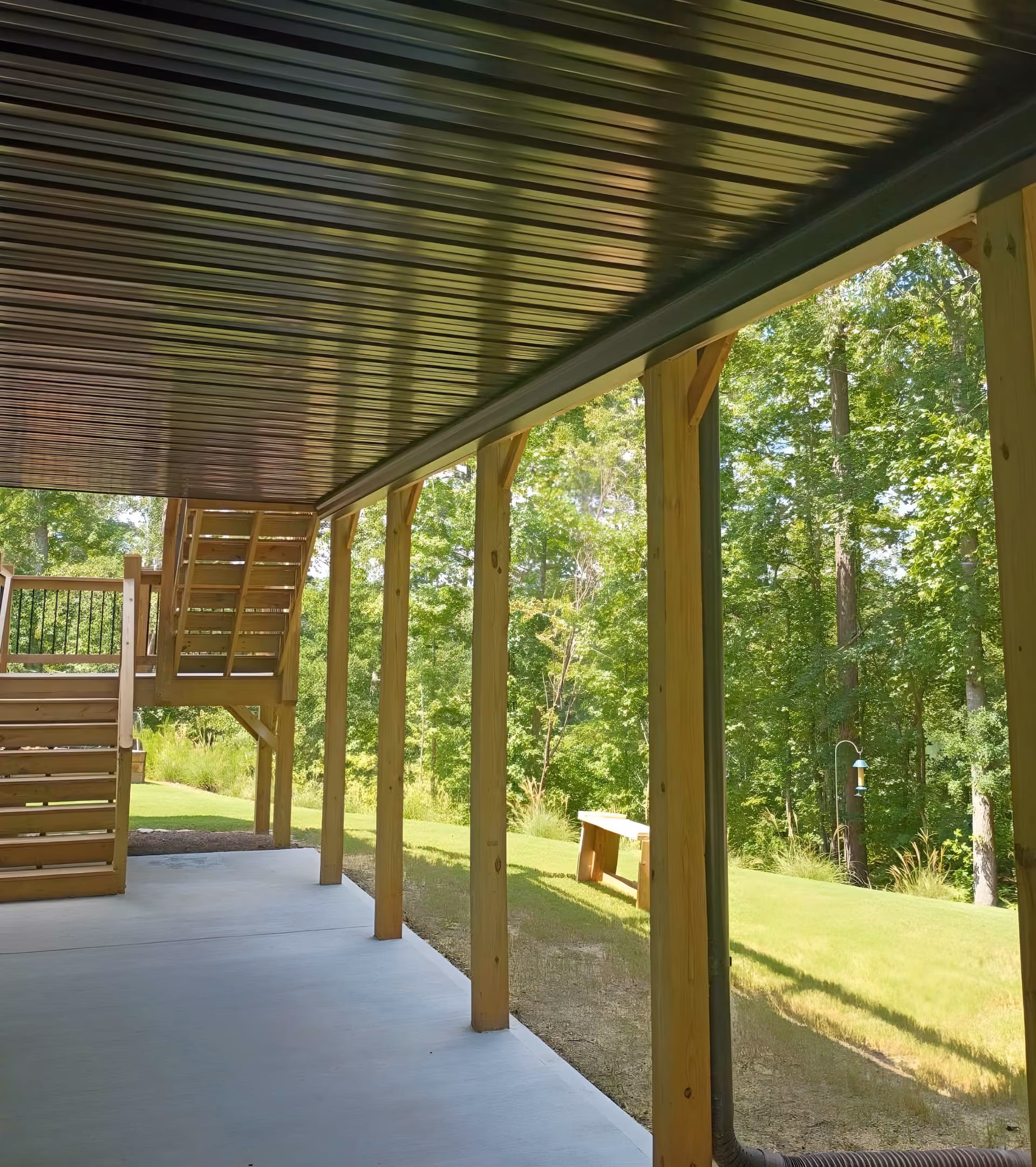Covered patio with a black corrugated metal ceiling and staircase to the level above