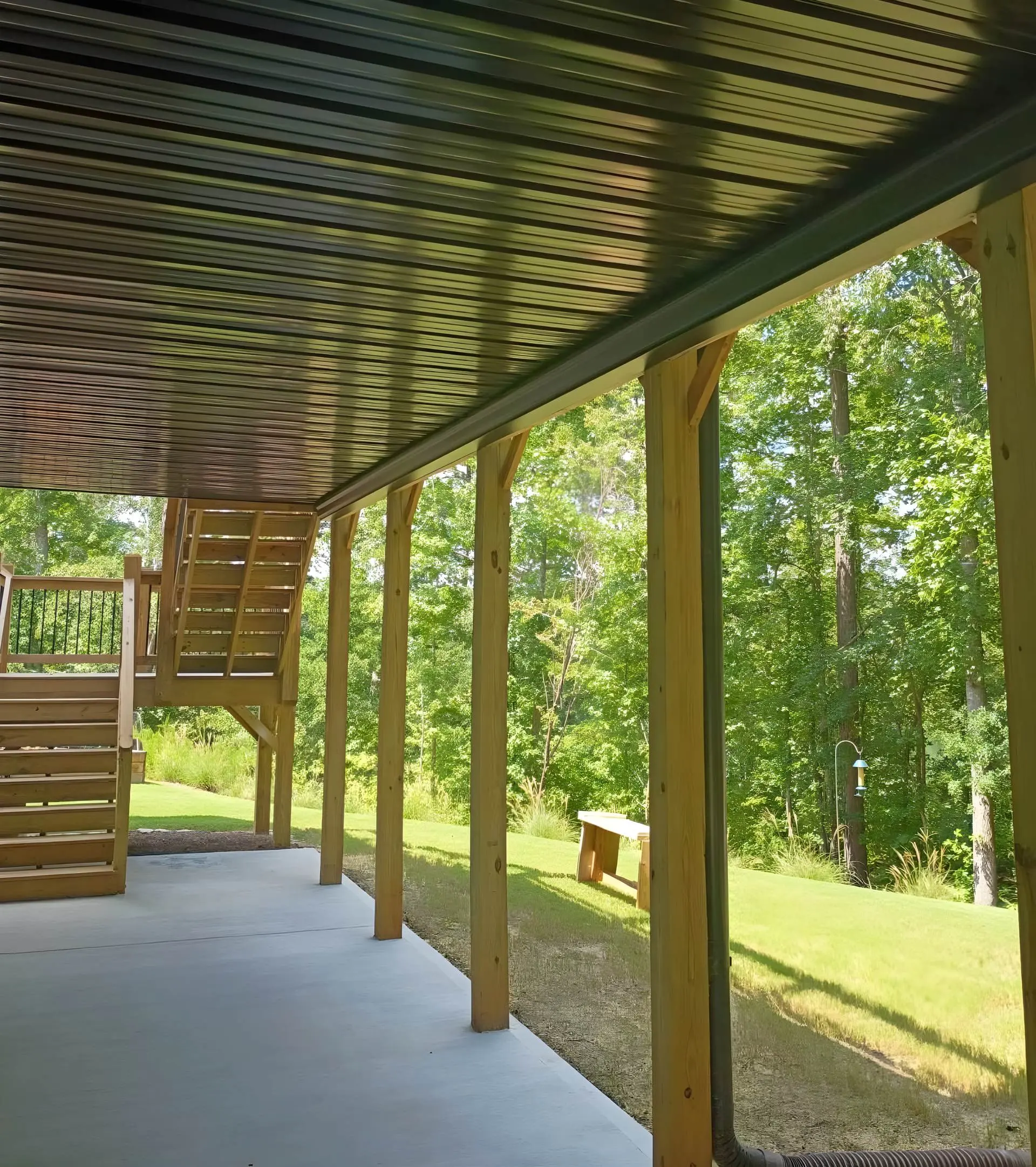 Covered patio with a black corrugated metal ceiling and staircase to the level above