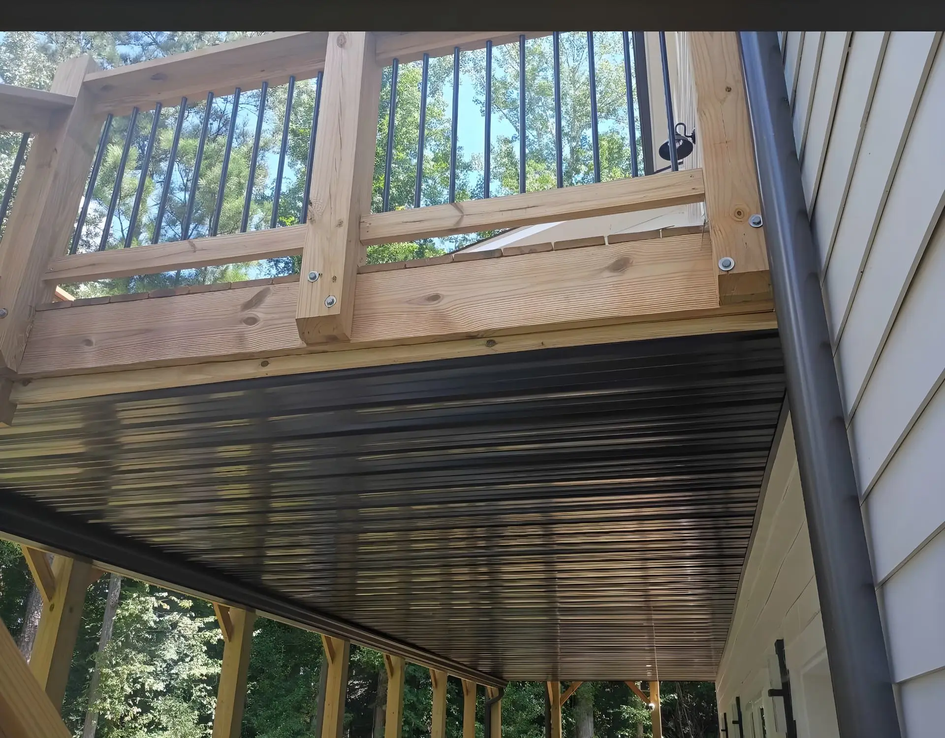 Covered patio support post with a black downspout tie-in, wall sconce lighting, and a glass door in the background.