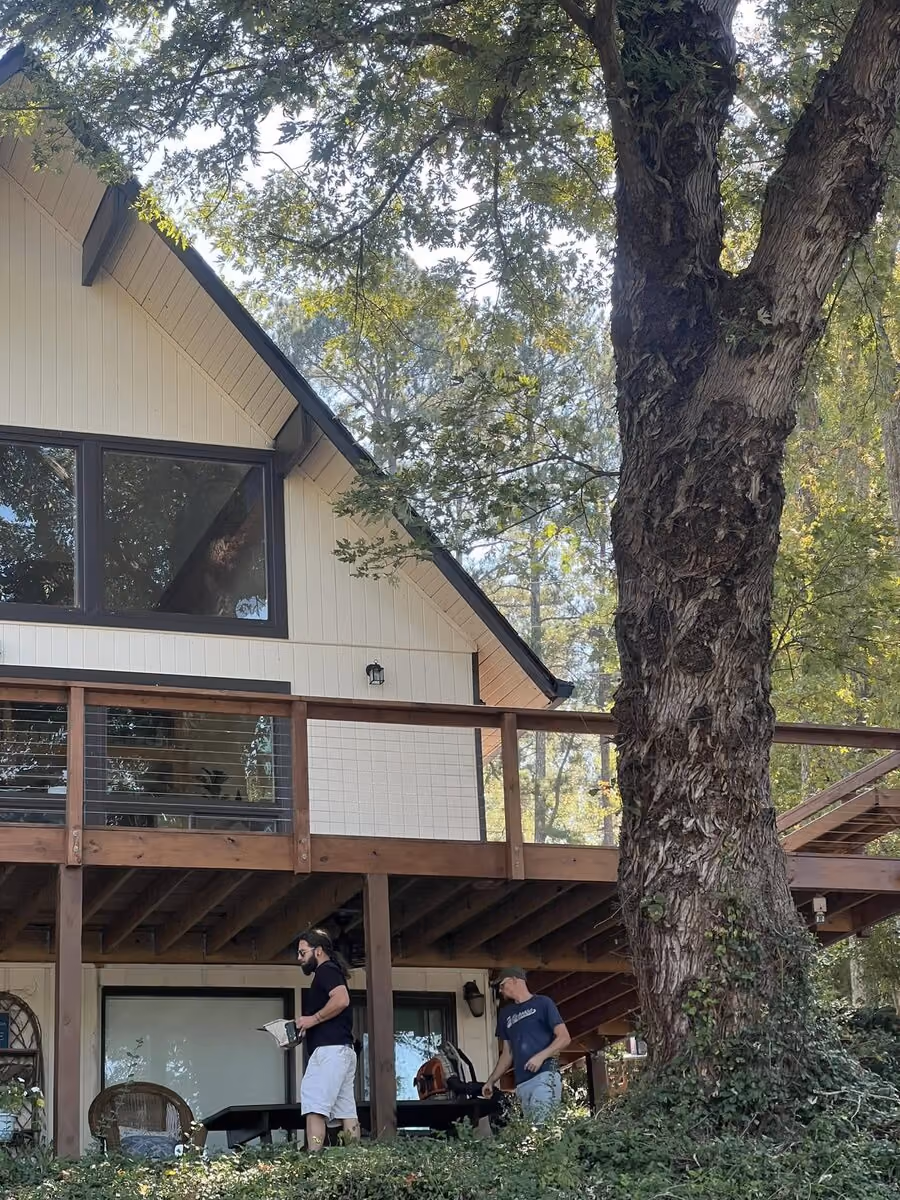 Crew on site at a redwood-stained wraparound deck with cable rail at an A-frame lake house