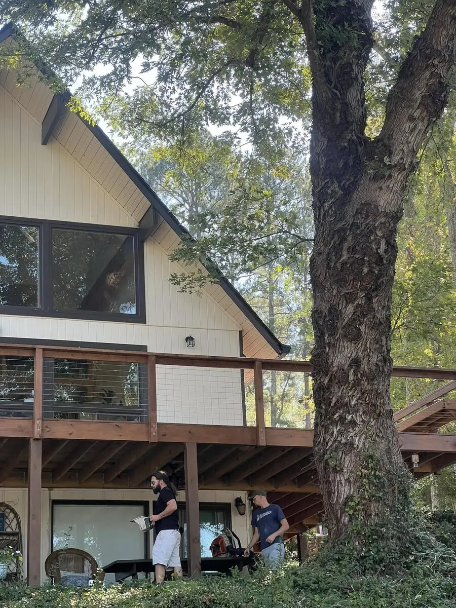 Crew on site at a redwood-stained wraparound deck with cable rail at an A-frame lake house