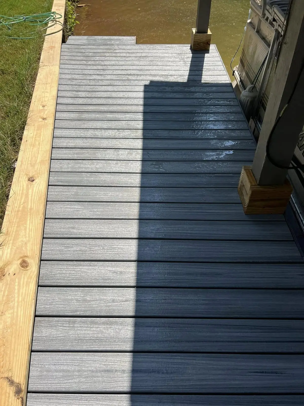 Gray composite decking installed on a lake dock with a pressure-treated border