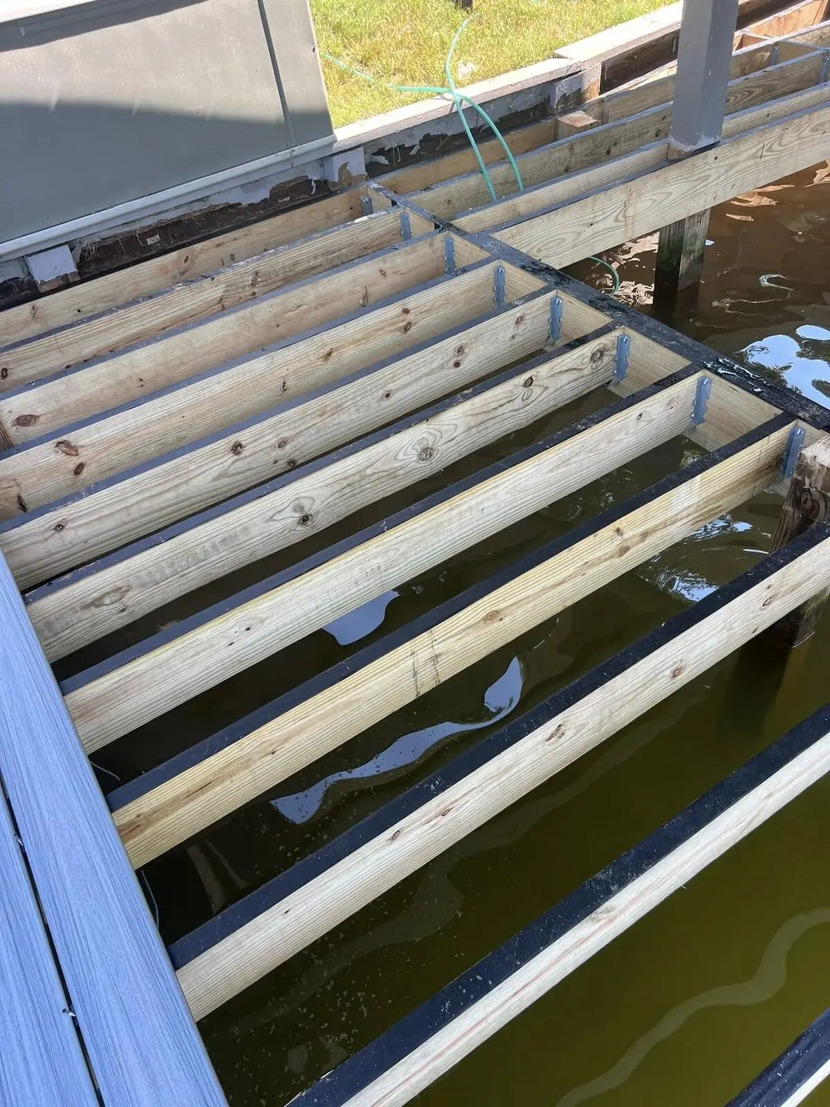 Pressure-treated dock joists and galvanized ties framed over lake water