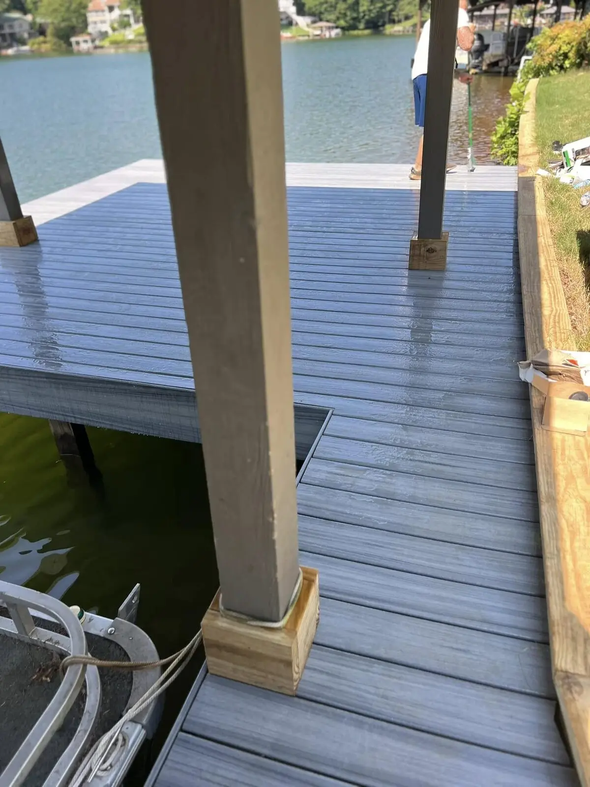 Dock decking being stained a dark gray-blue at Fairfield Plantation, a worker rolling the stain onto the boards