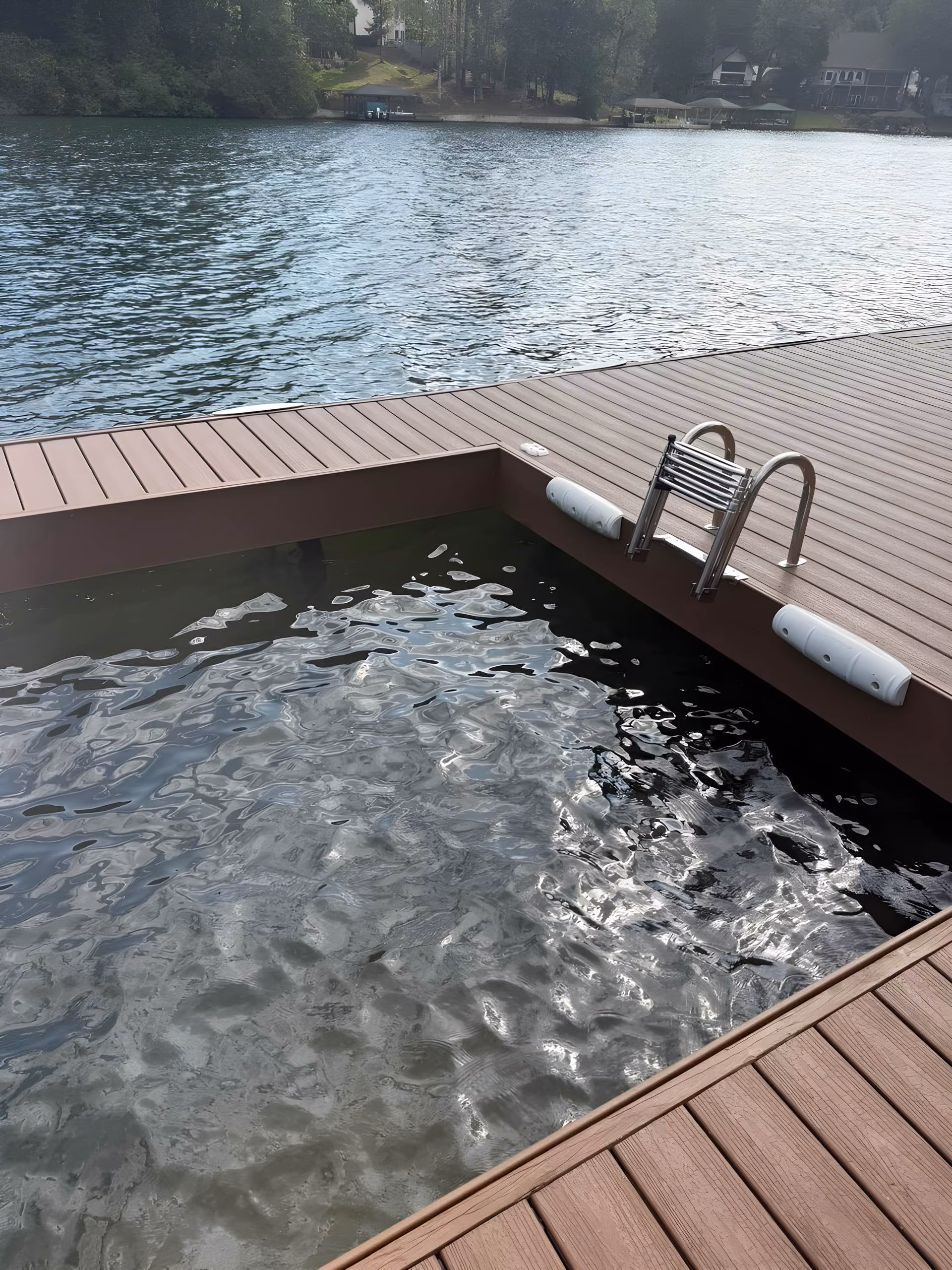 Dock corner with a stainless swim ladder over dark lake water