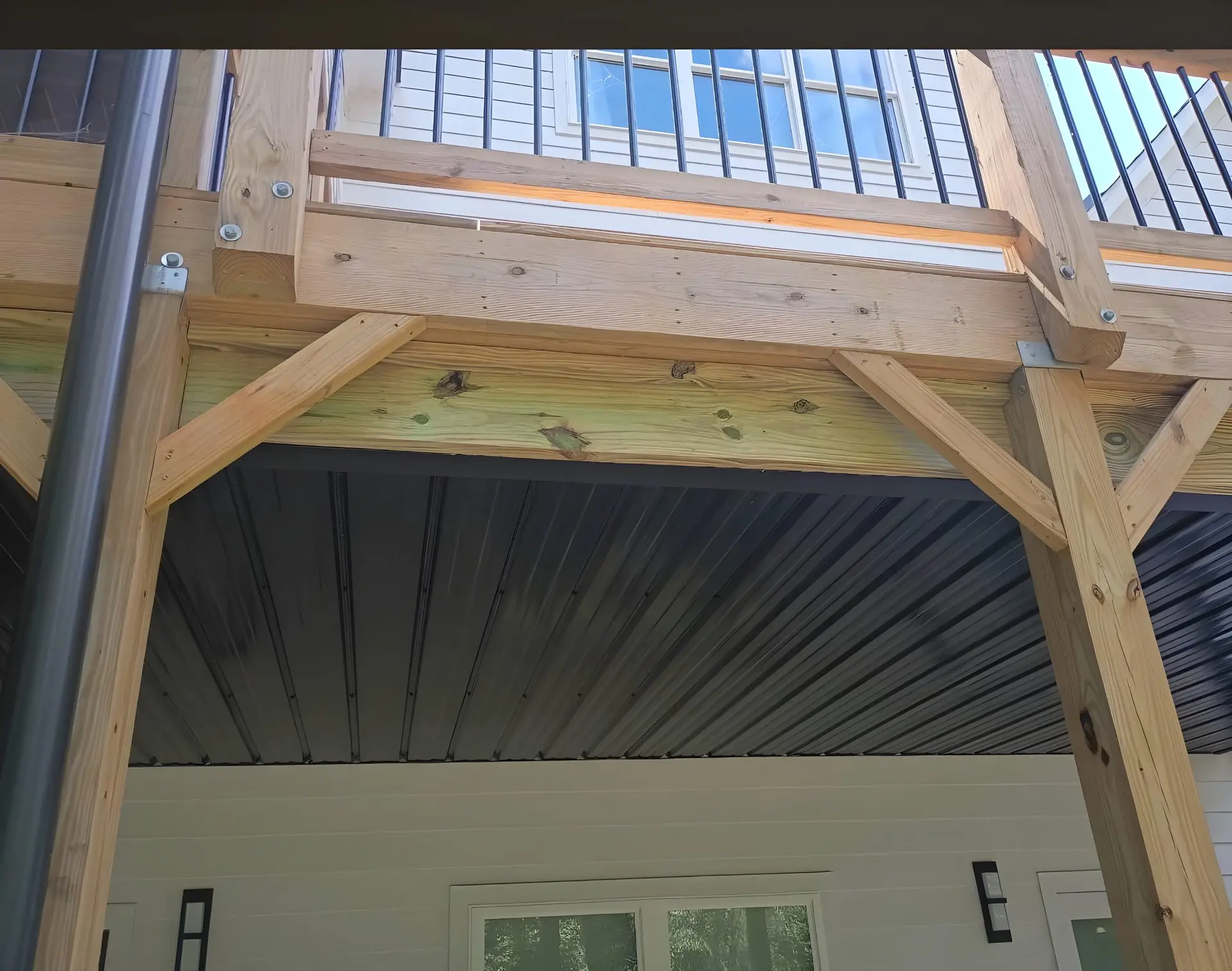 Underside of an elevated deck showing pressure-treated posts and beams supporting the floor above