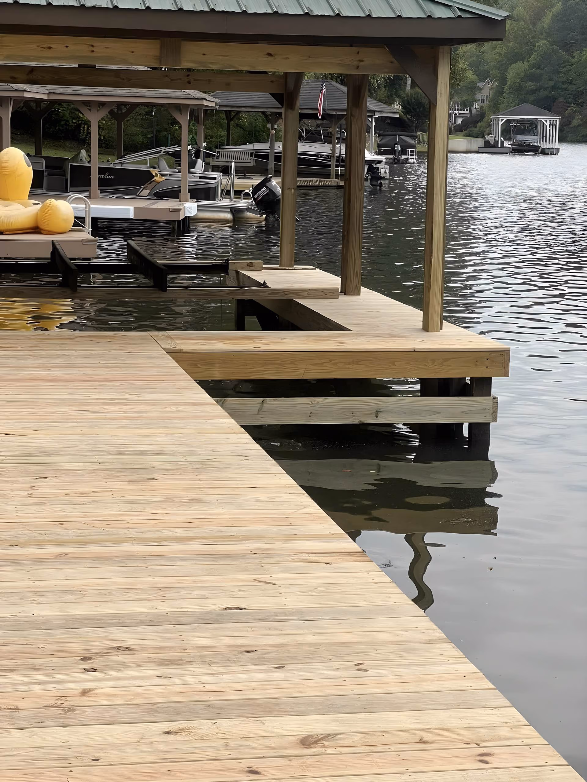 New pressure-treated dock decking and a covered slip on a west Georgia lake, with boathouses across the cove