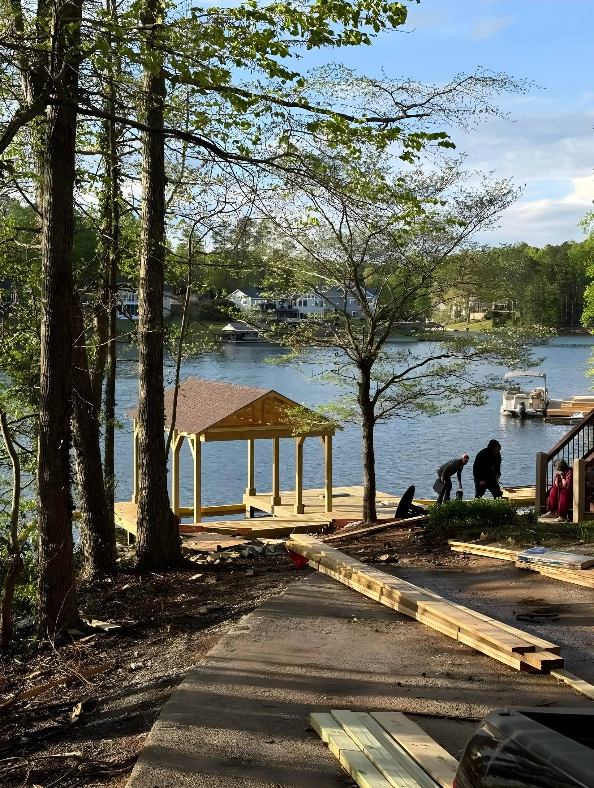 New boathouse/dock build along the shoreline; crew present with construction materials staged on the ground.
