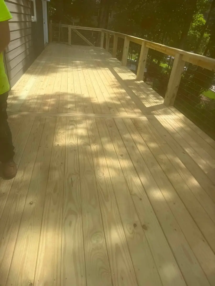 Close-up of new pressure-treated deck flooring and cable railing under construction