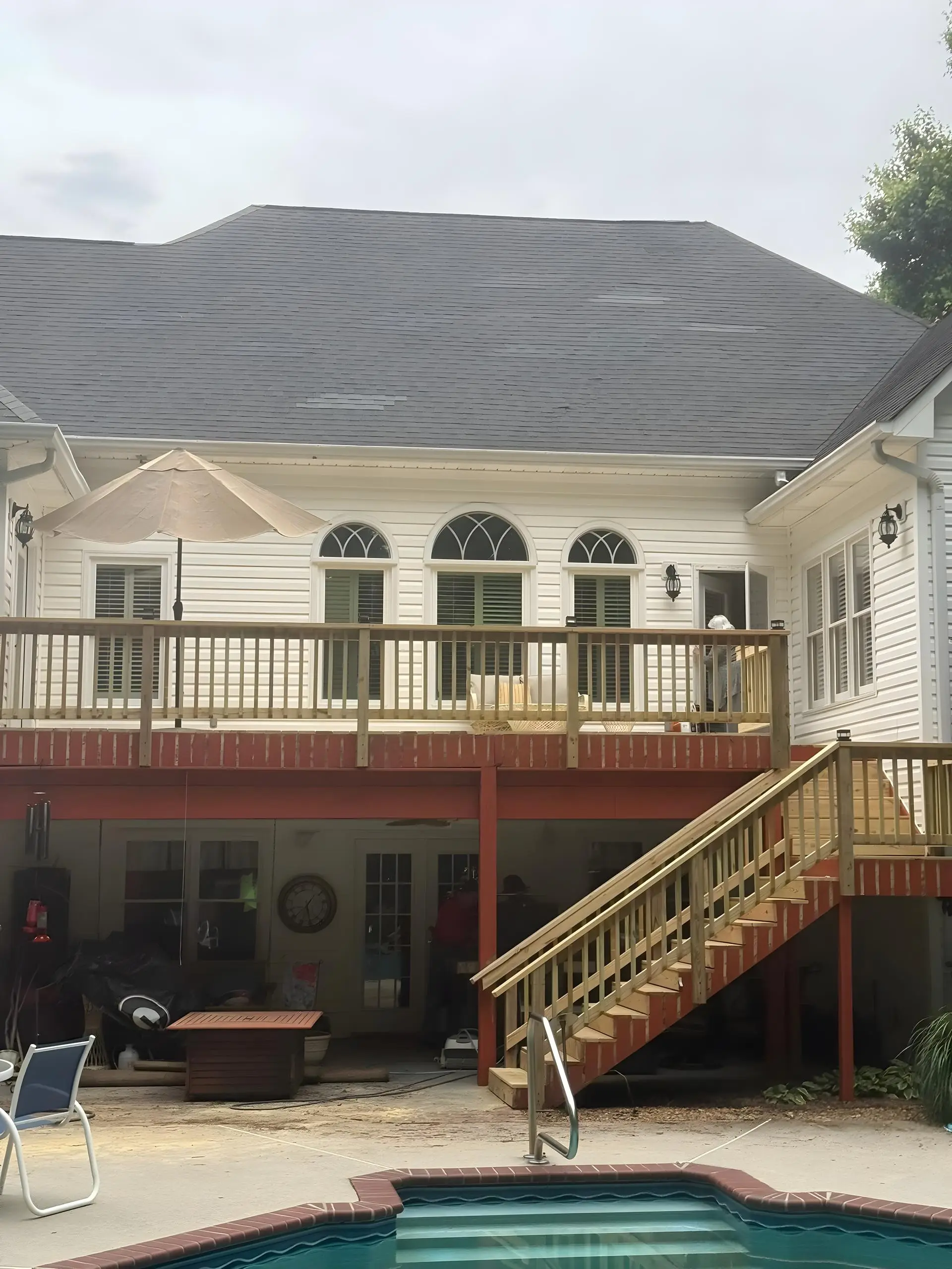 Poolside second-story deck rebuild with new stairs down to the pool patio at a white colonial home