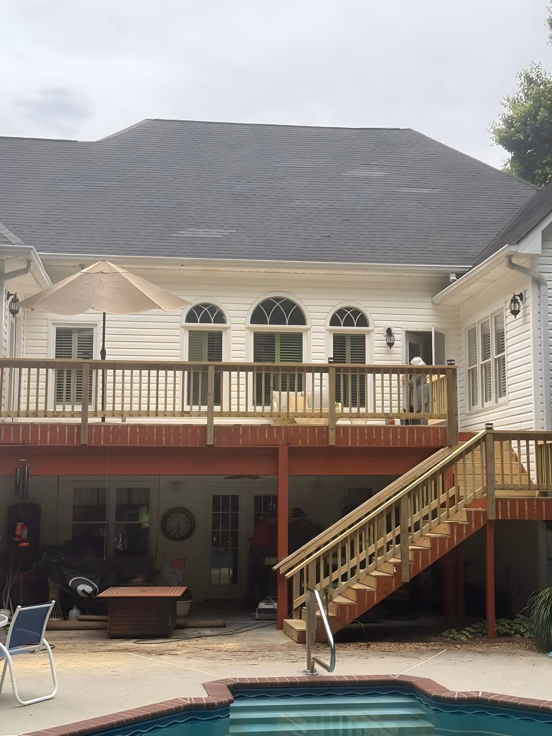 Poolside second-story deck rebuild with new stairs down to the pool patio at a white colonial home