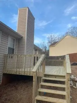 New pressure-treated deck with wide stairs on the side of a split-level home