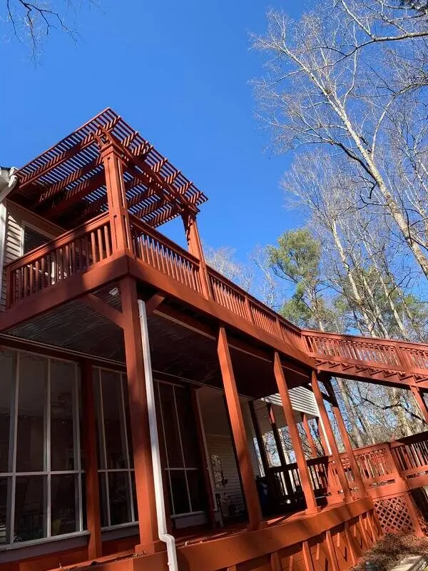 Red-stained multi-level deck and pergola built over a screened porch at a wooded West Georgia home