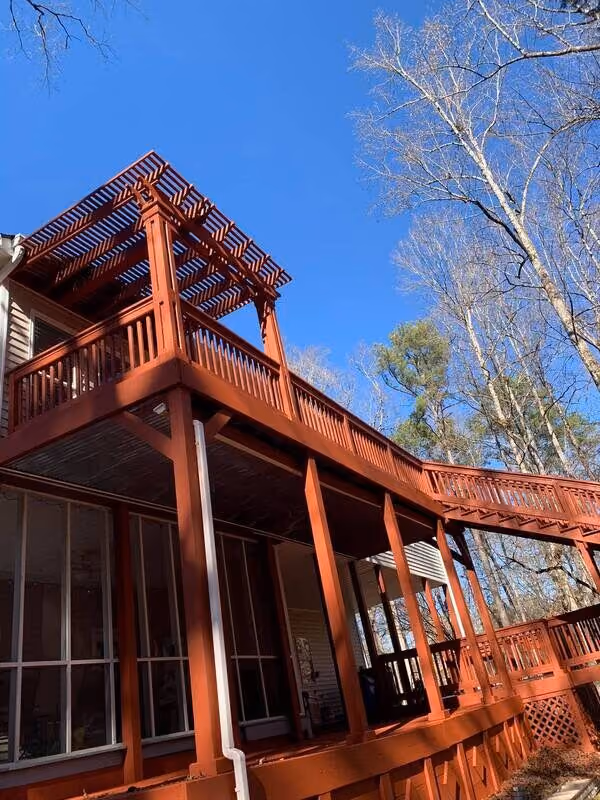 Red-stained multi-level deck with a pergola over a screened porch
